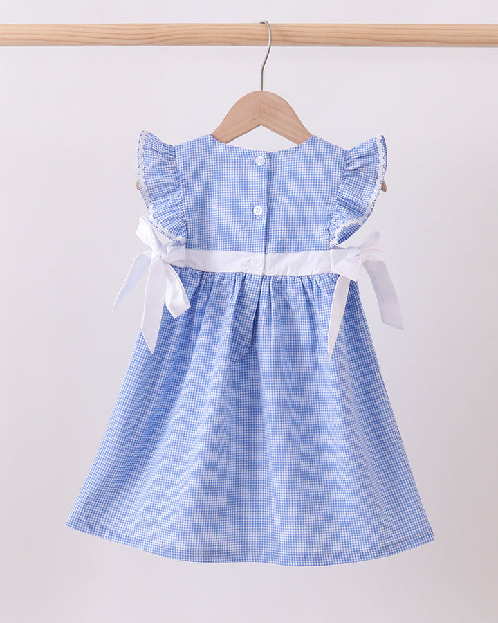 Blue checkered dress with white ribbon on a wooden hanger against a white background
