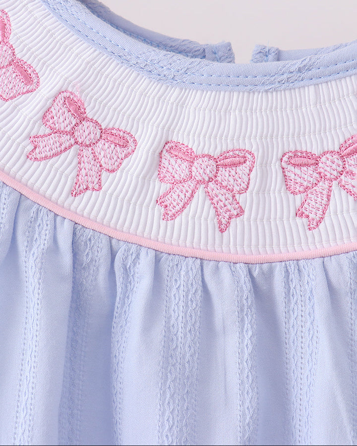 Light blue dress with pink bow details on a wooden hanger
