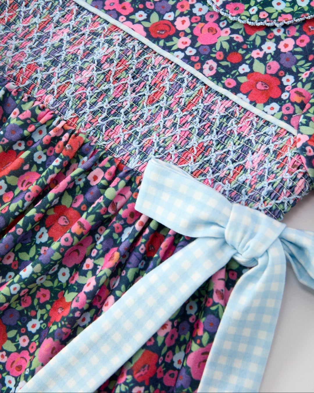 Close-up: smocked bodice floral dress with light blue gingham bow tie