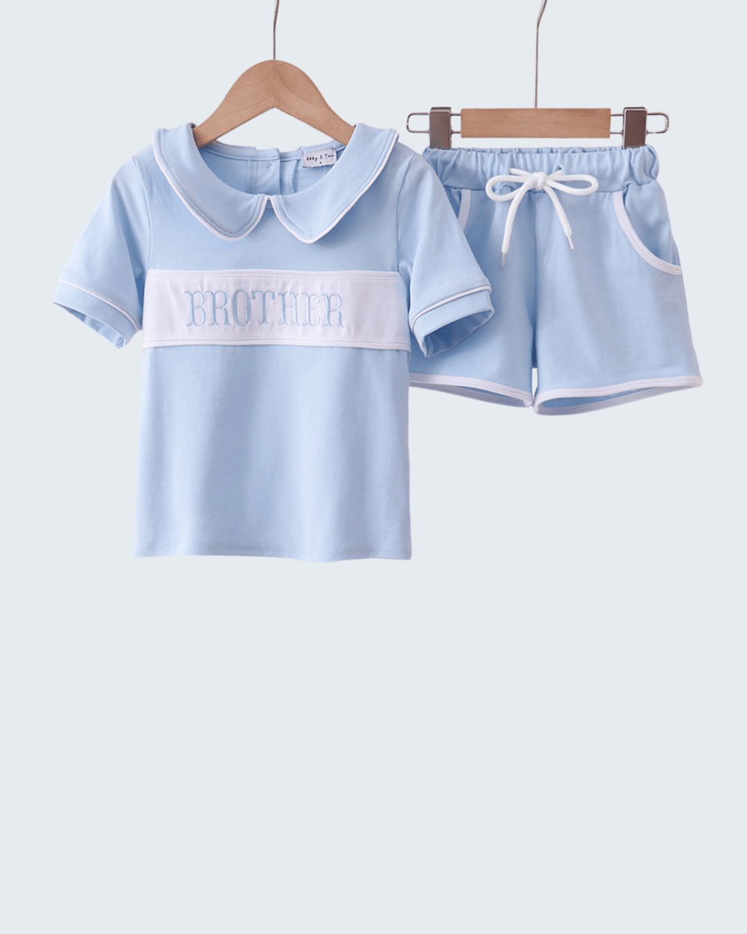 Light blue children's outfit with a shirt and shorts on hangers against a white background