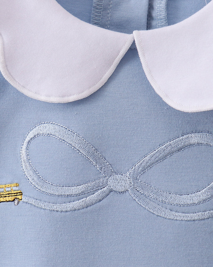 Light blue top close-up: white scalloped collar and stitched bus bow embroidery
