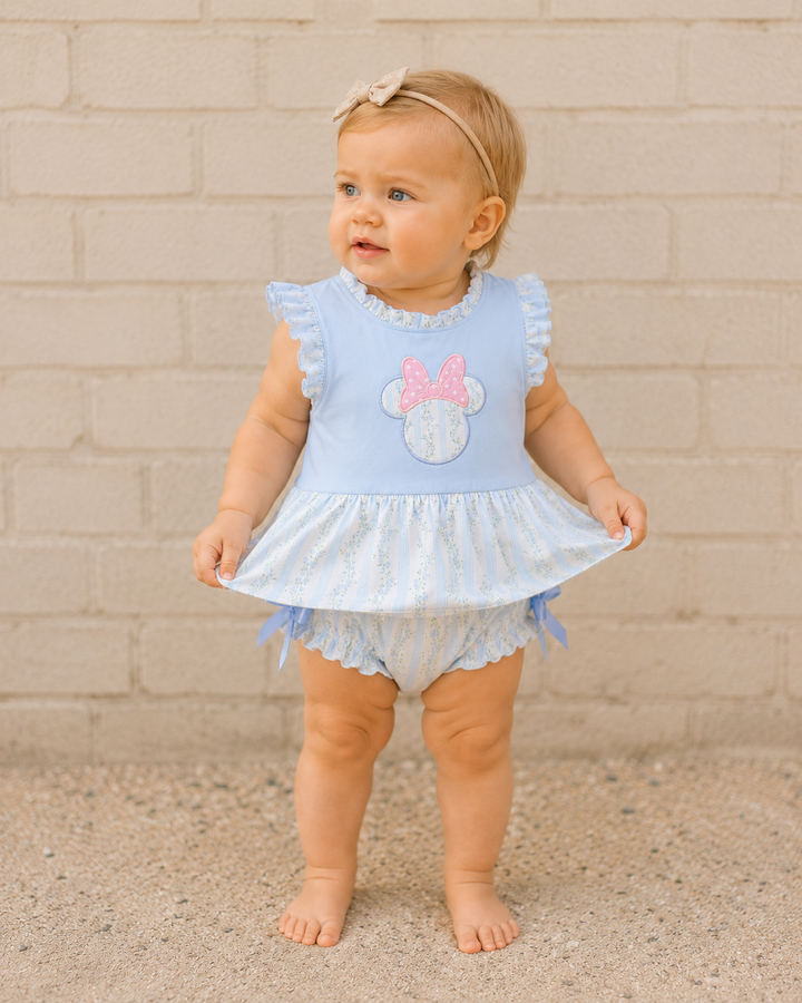 Infant girl in front of brick wall.