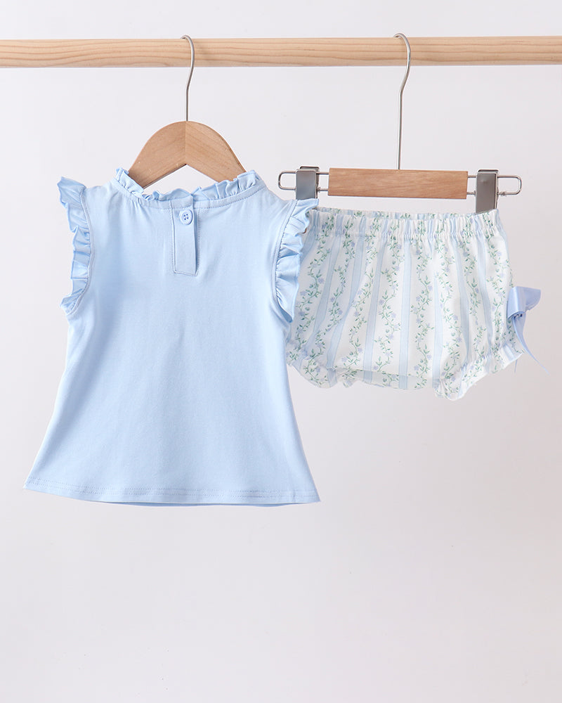 Light blue top and floral shorts on hangers against a light background