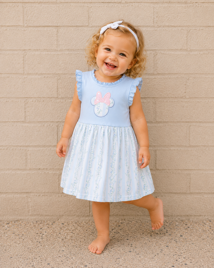 Toddler girl in front of light brick wall.