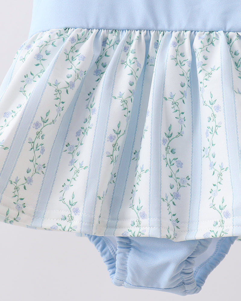 Light blue and white floral patterned baby bloomers on a light gray background