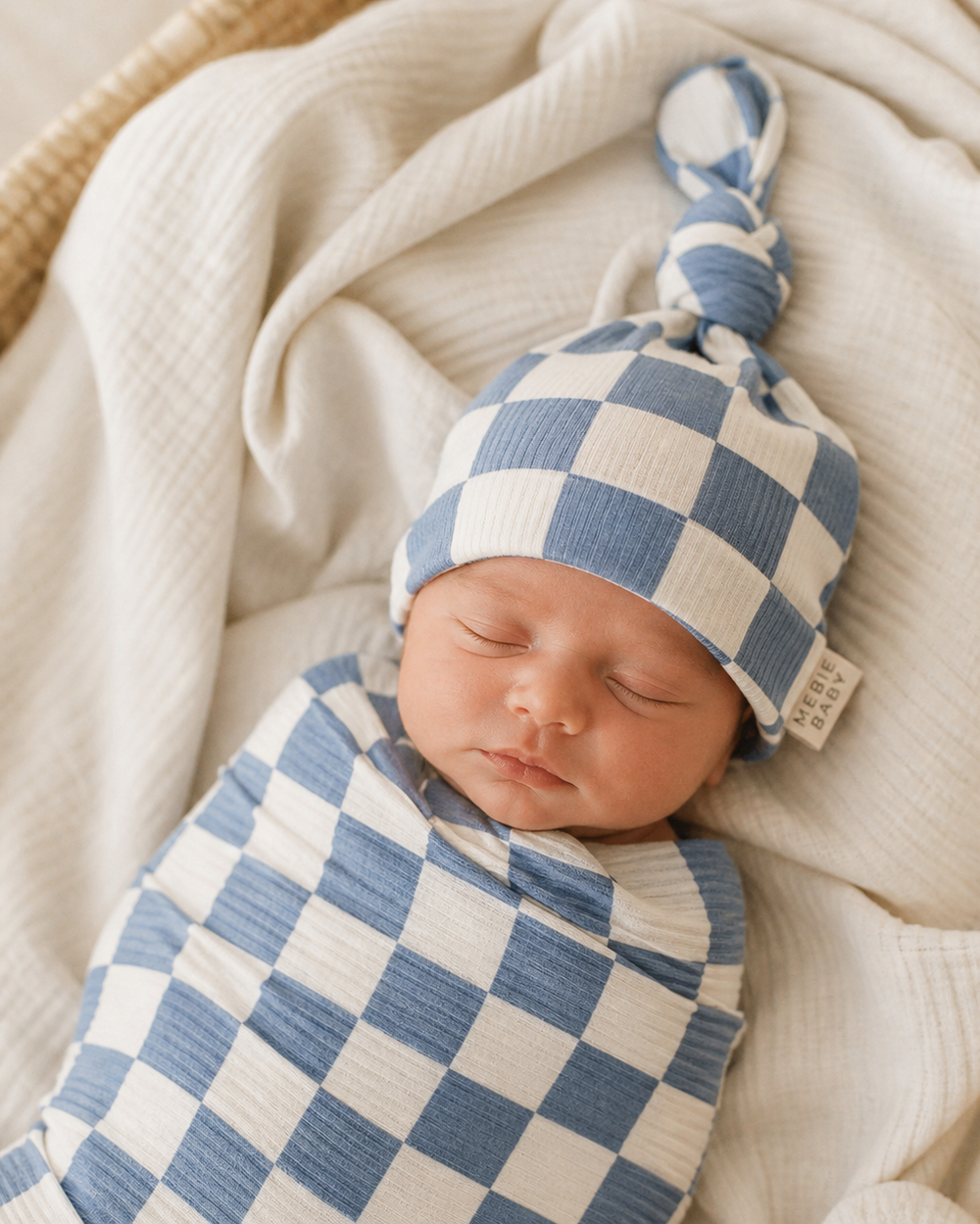 Newborn baby wrapped in a blue and white checkered blanket with matching hat.