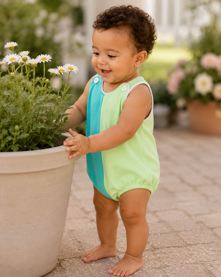 Baby boy looking at flowers in a flower pot