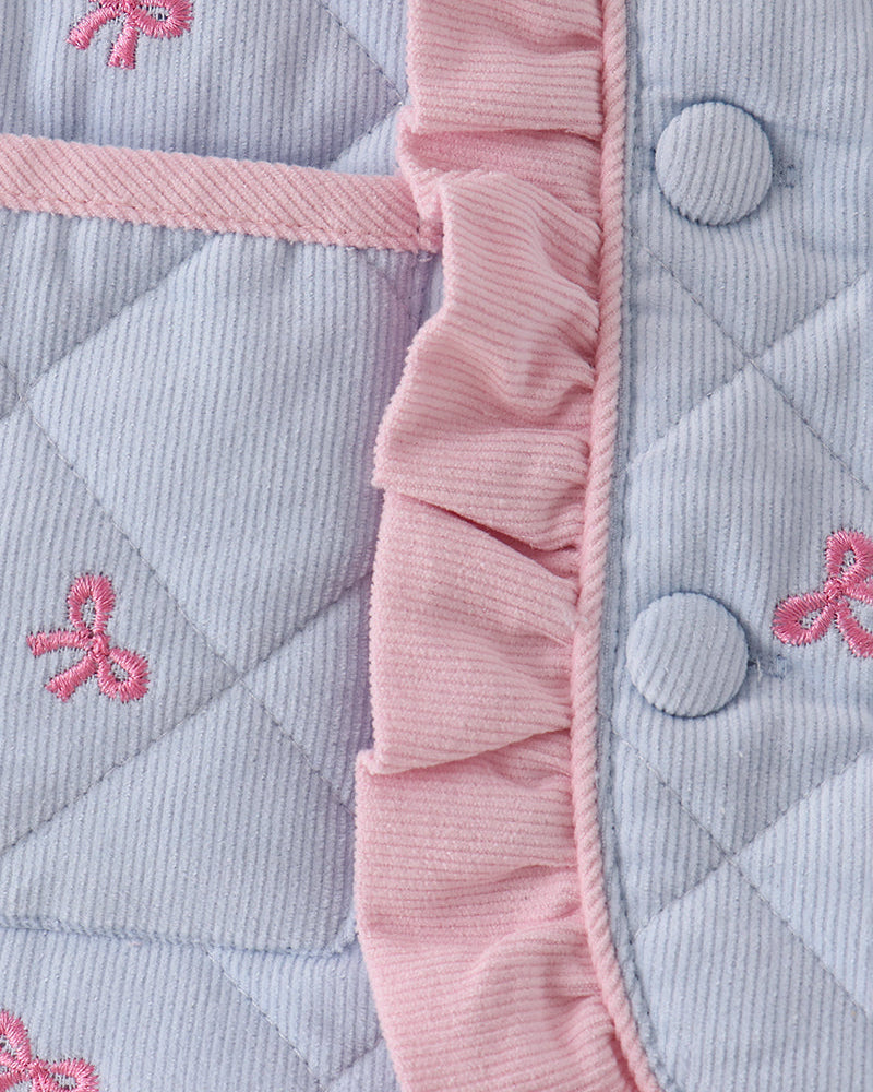 Light blue quilted fabric with pink bow embroidery and pink ruffled trim at placket