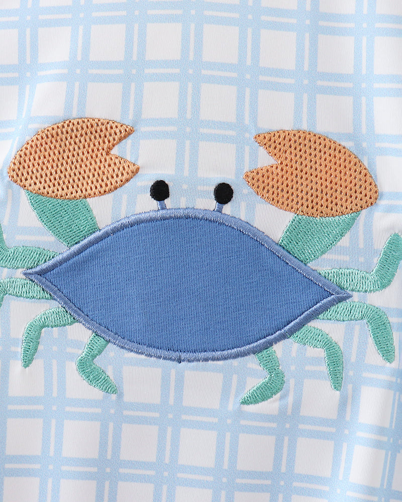 Embroidered crab design on a checkered fabric background