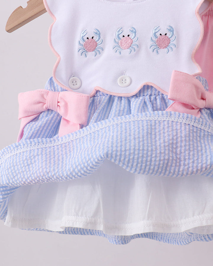Baby outfit with bib, shirt, and shorts featuring crab designs on a light gray background.