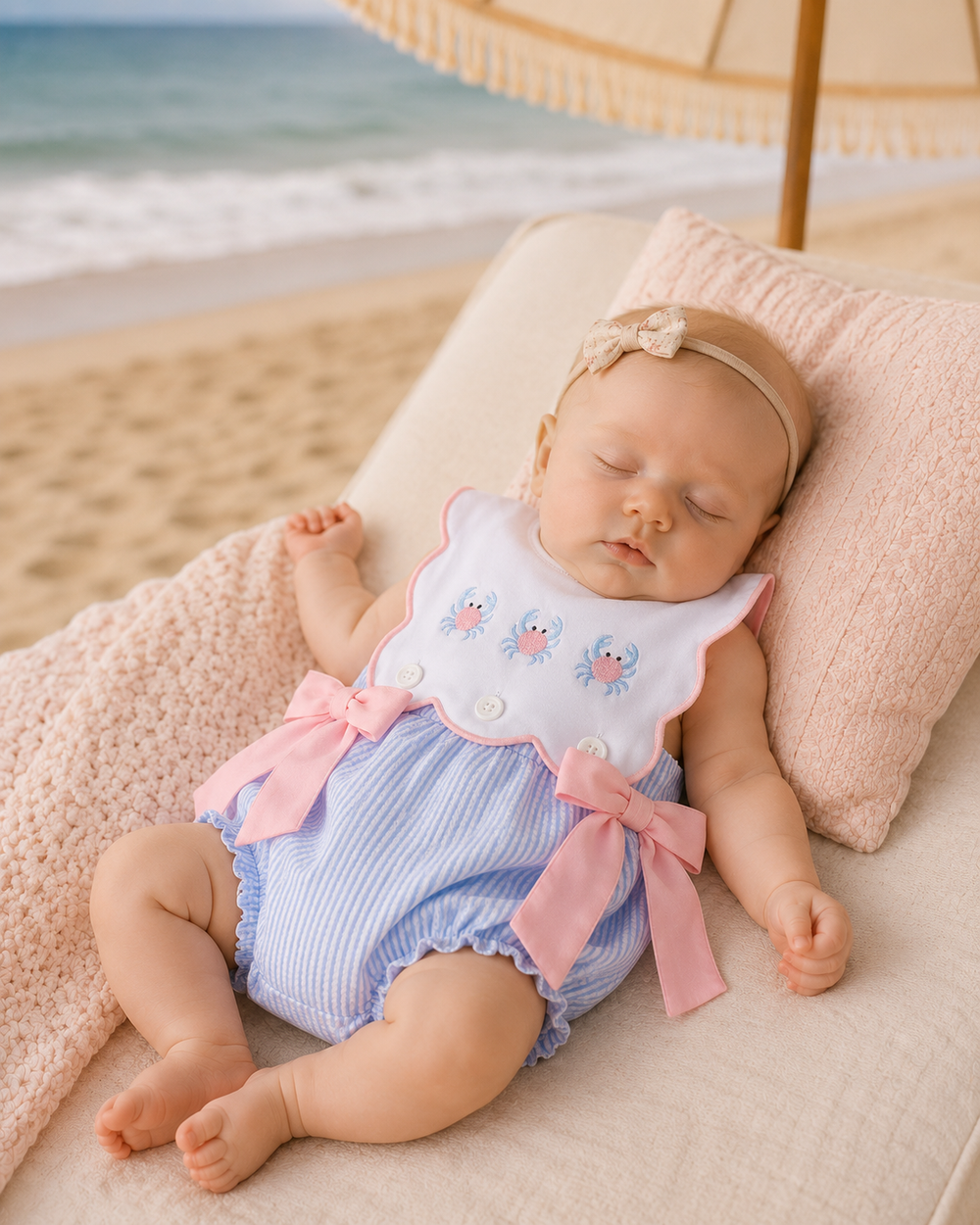 Infant girl sleeping on a beach bed under an umbrella.