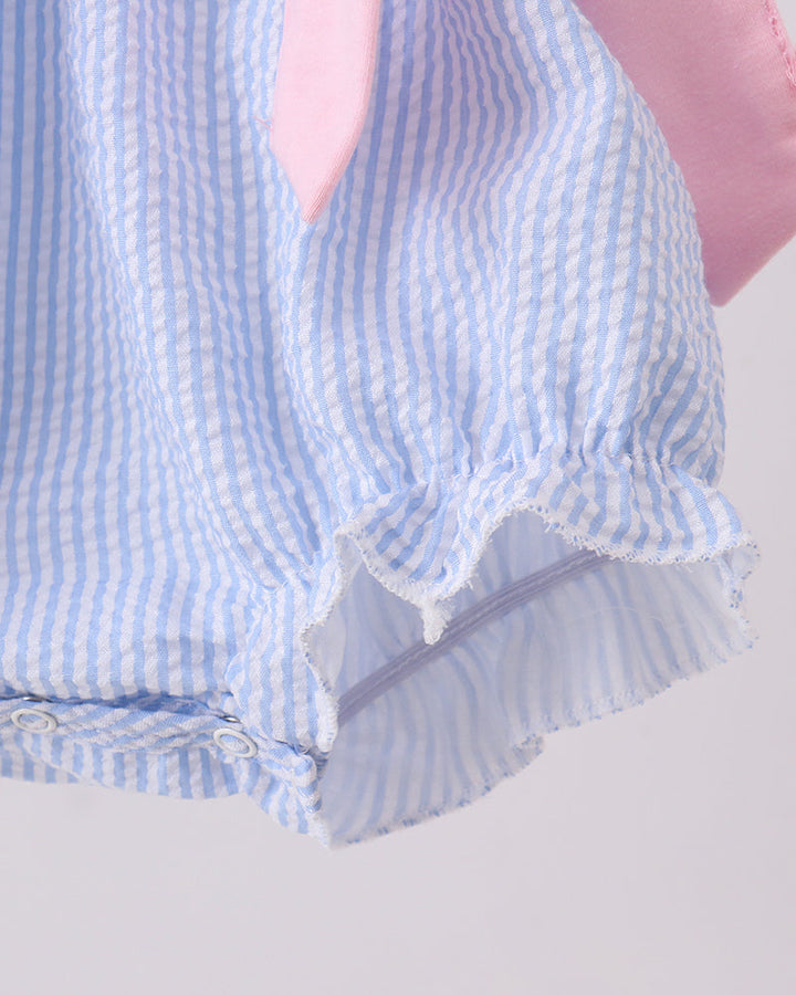 Close-up of a blue and white striped garment with ruffled trim on a light gray background