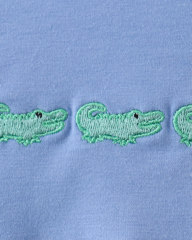 Light blue romper with green crocodile embroidery and ruffled trim