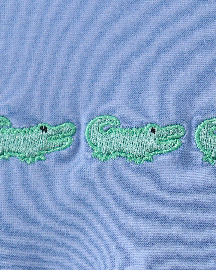 Light blue romper with green crocodile embroidery and ruffled trim
