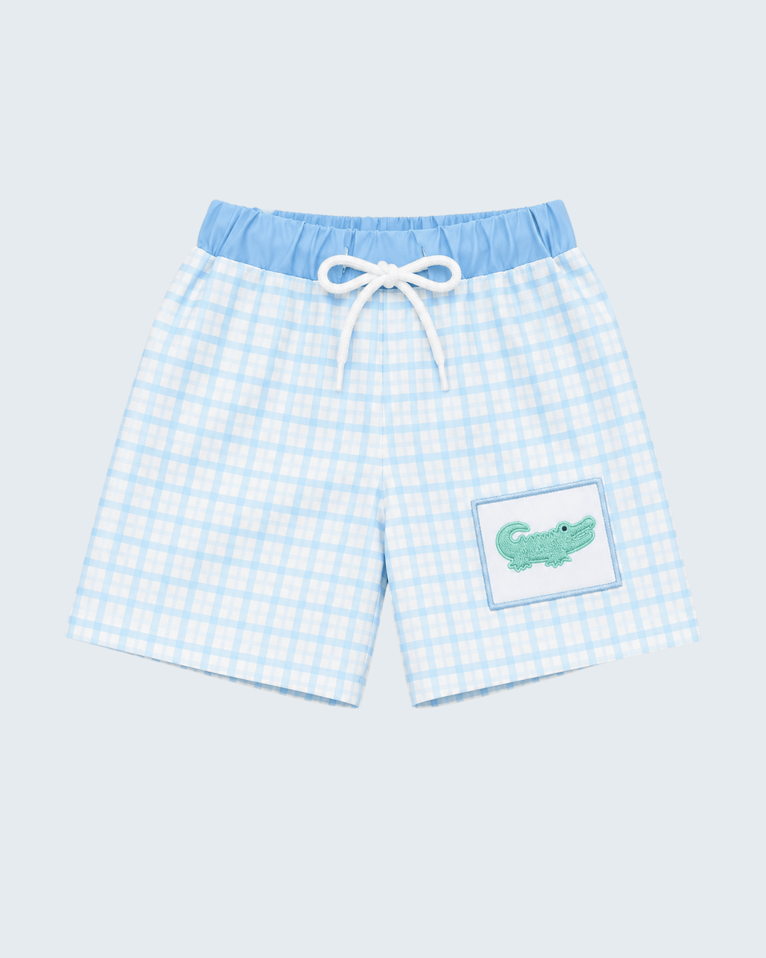 Light blue plaid swim trunks with white drawstring and green crocodile logo patch.