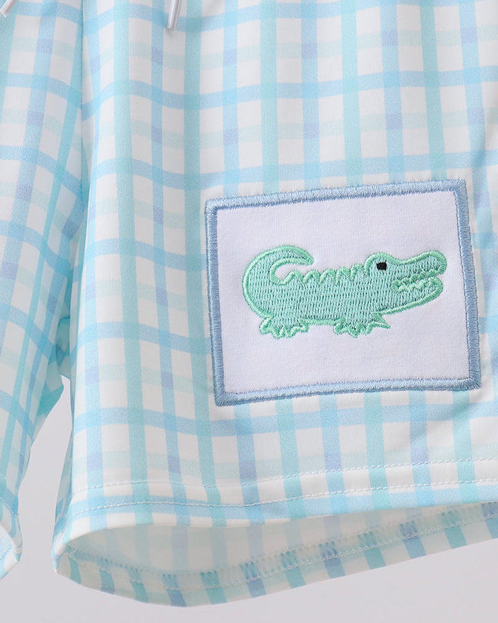 Light blue plaid swim trunks with green crocodile patch on the front pocket.