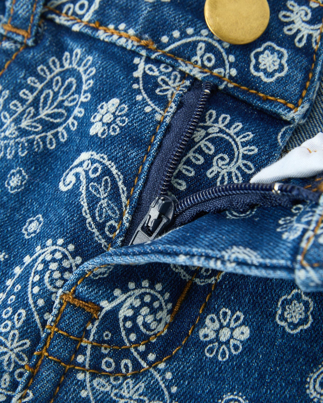 Girls blue denim jeans close-up with white paisley print, zip fly and top button