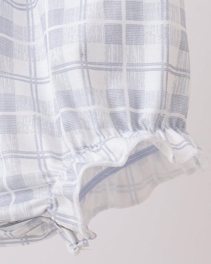 Baby romper close-up: white plaid with ruffled hem and side tie detail