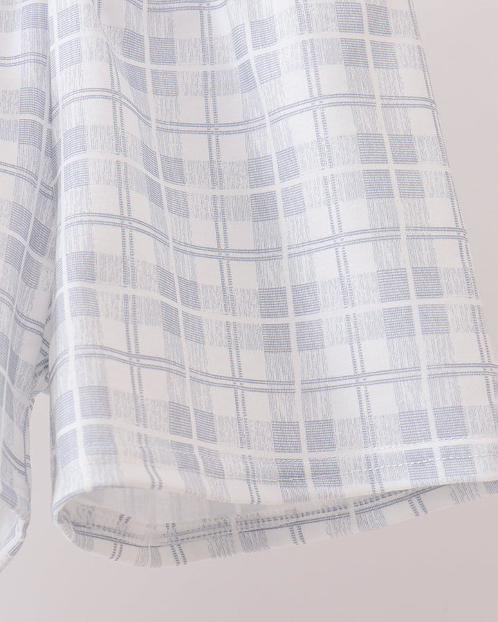Light blue and white plaid shorts fabric close-up with stitched hem