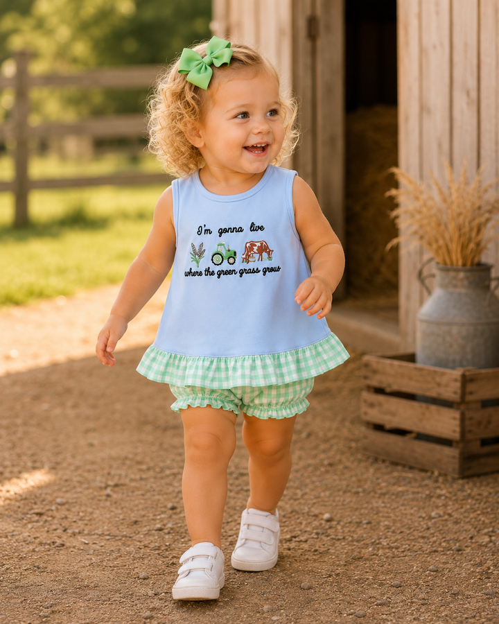 Child wearing a light blue sleeveless top with text and checkered shorts outdoors.