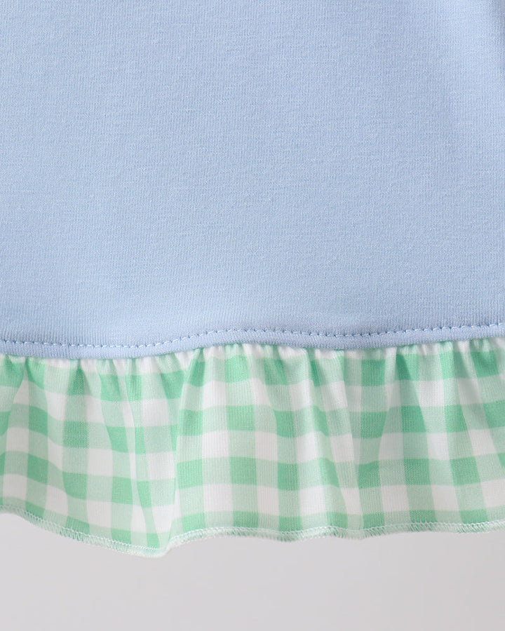 Close-up of a light blue fabric with a green and white checkered trim on a plain background