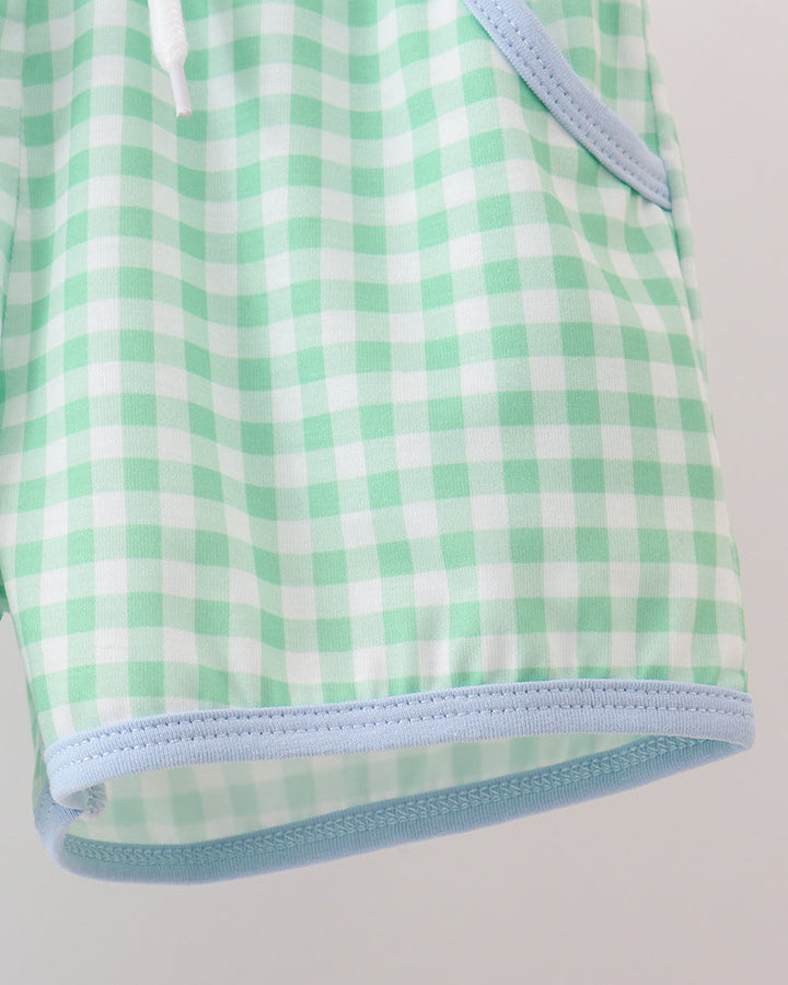 Green and white checkered baby outfit with light blue trim on a gray background