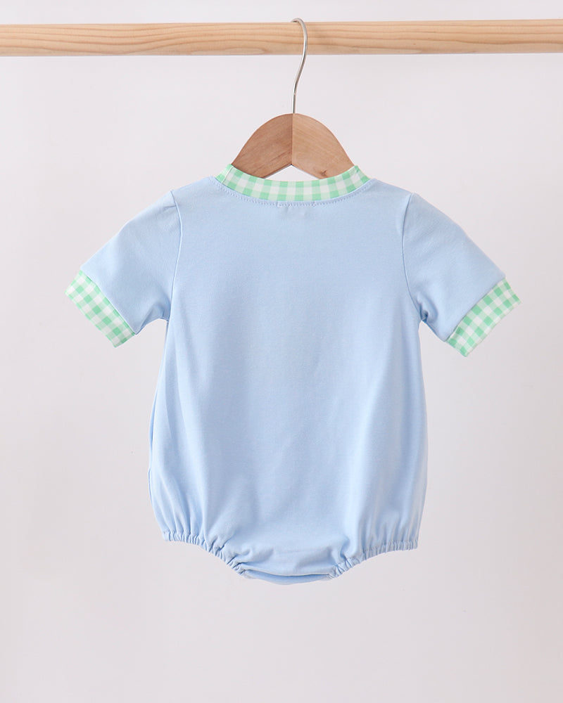 Light blue baby romper with green checkered collar on a wooden hanger against a light background