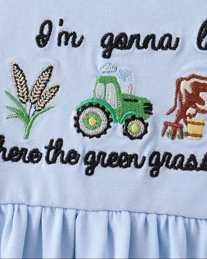 Light blue dress with embroidered green tractor, cow, and text on a checkered collar.