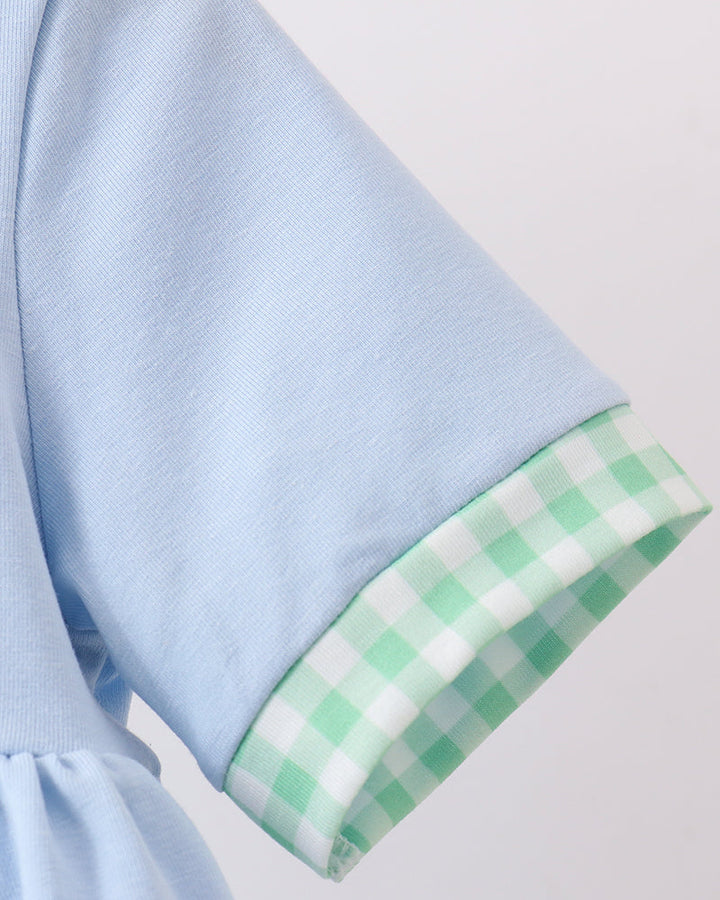 Light blue fabric with a green checkered trim on a light gray background