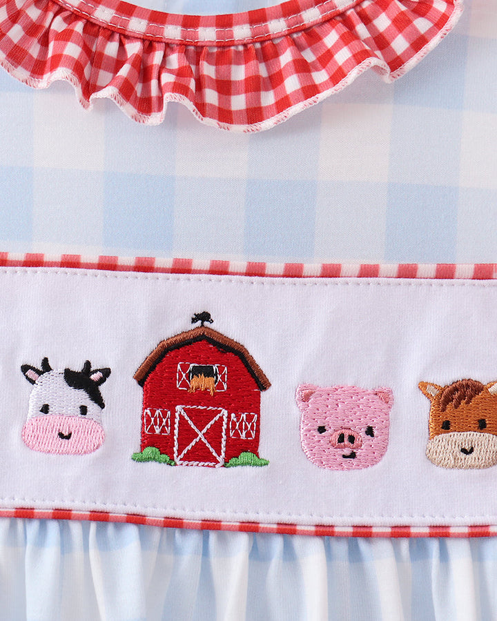 Close-up of light blue gingham dress with red gingham ruffle and animal scene embroidery