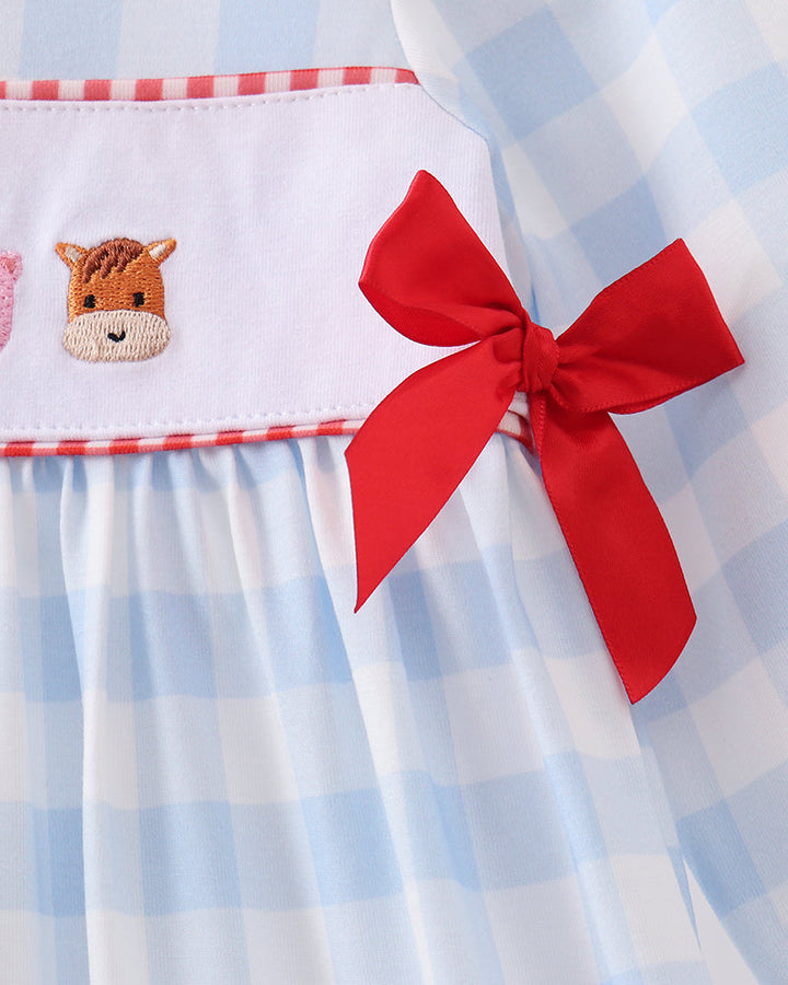 Light blue gingham dress detail with red bow at waist and animal embroidery patch