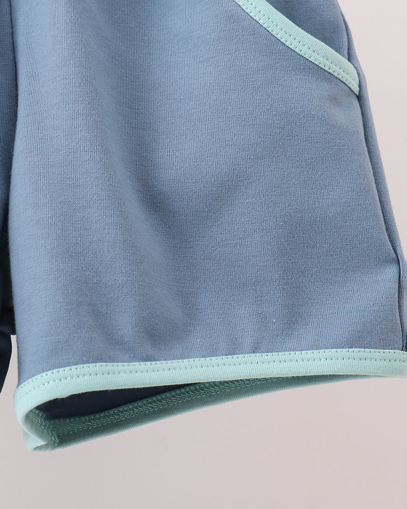 Close-up of a light blue garment with pale mint green contrast trim along the edge.