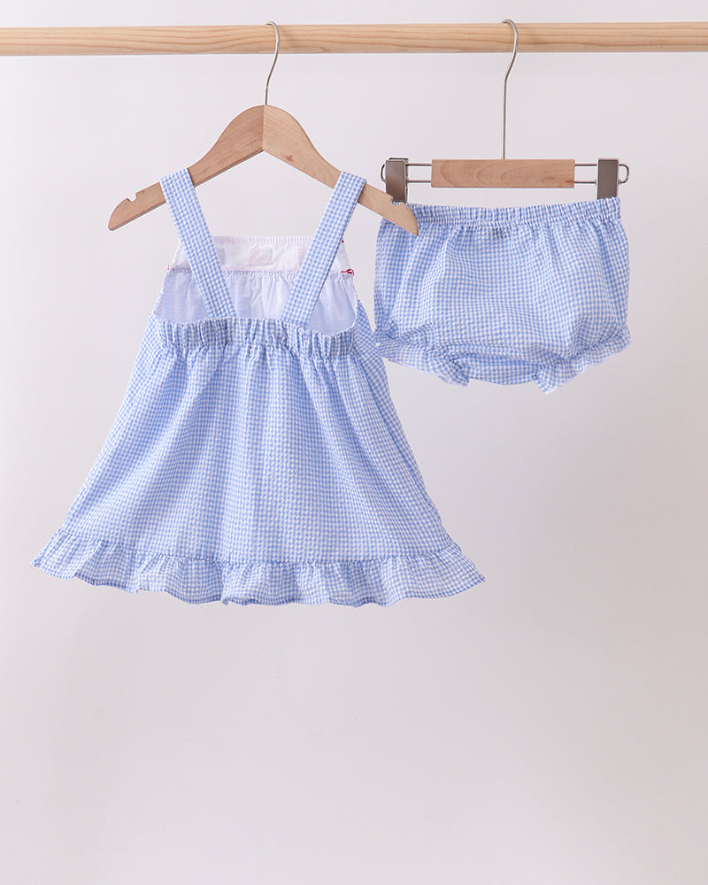 Baby dress and bloomers set with blue checkered pattern on hangers against a white background