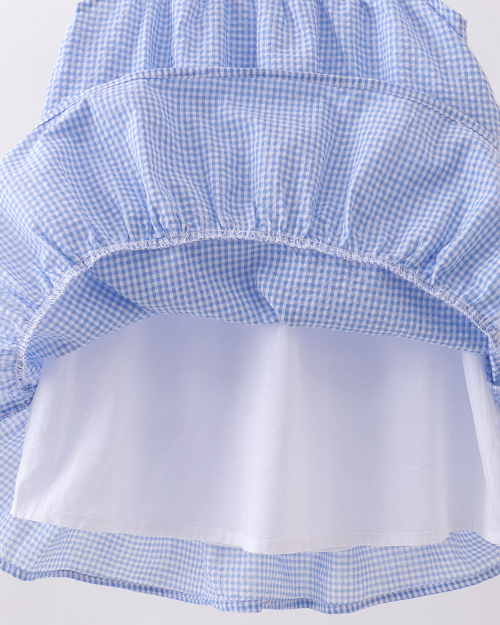Blue checkered dress with a white underlayer on a light gray background