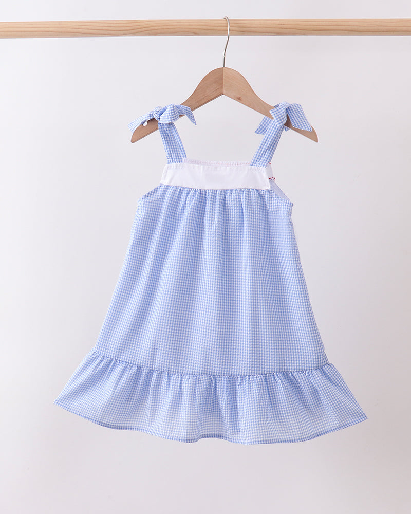 Blue checkered dress with ruffled skirt on a hanger against a white background