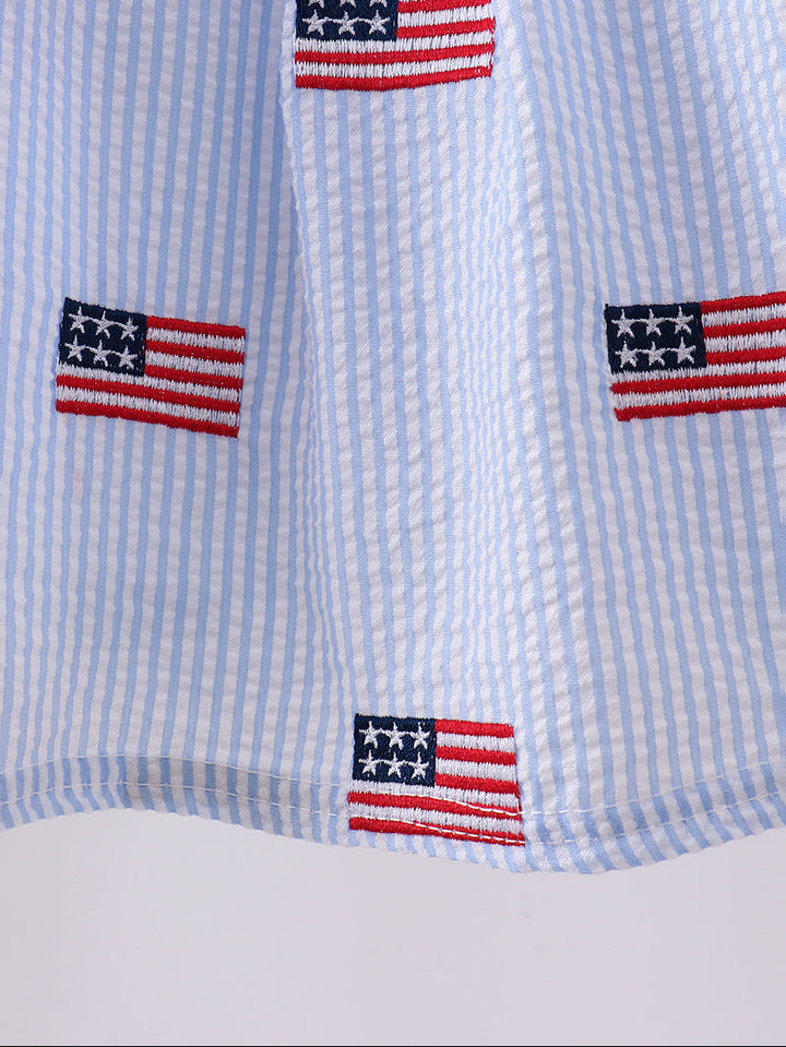 Close-up of a shirt with embroidered American flags on a blue and white striped background
