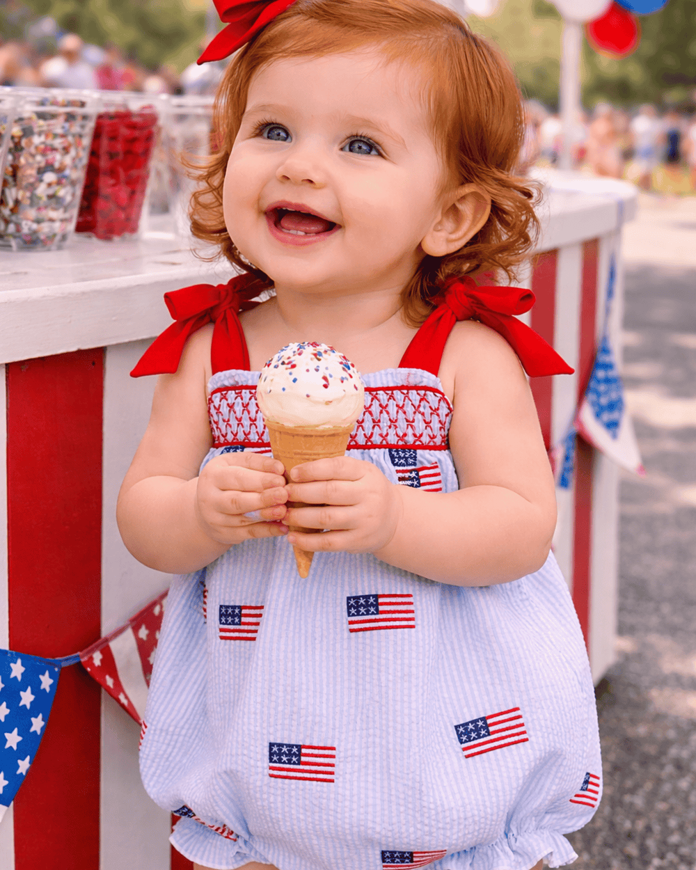 Child in a patriotic outfit holding an ice cream cone with a blurred background