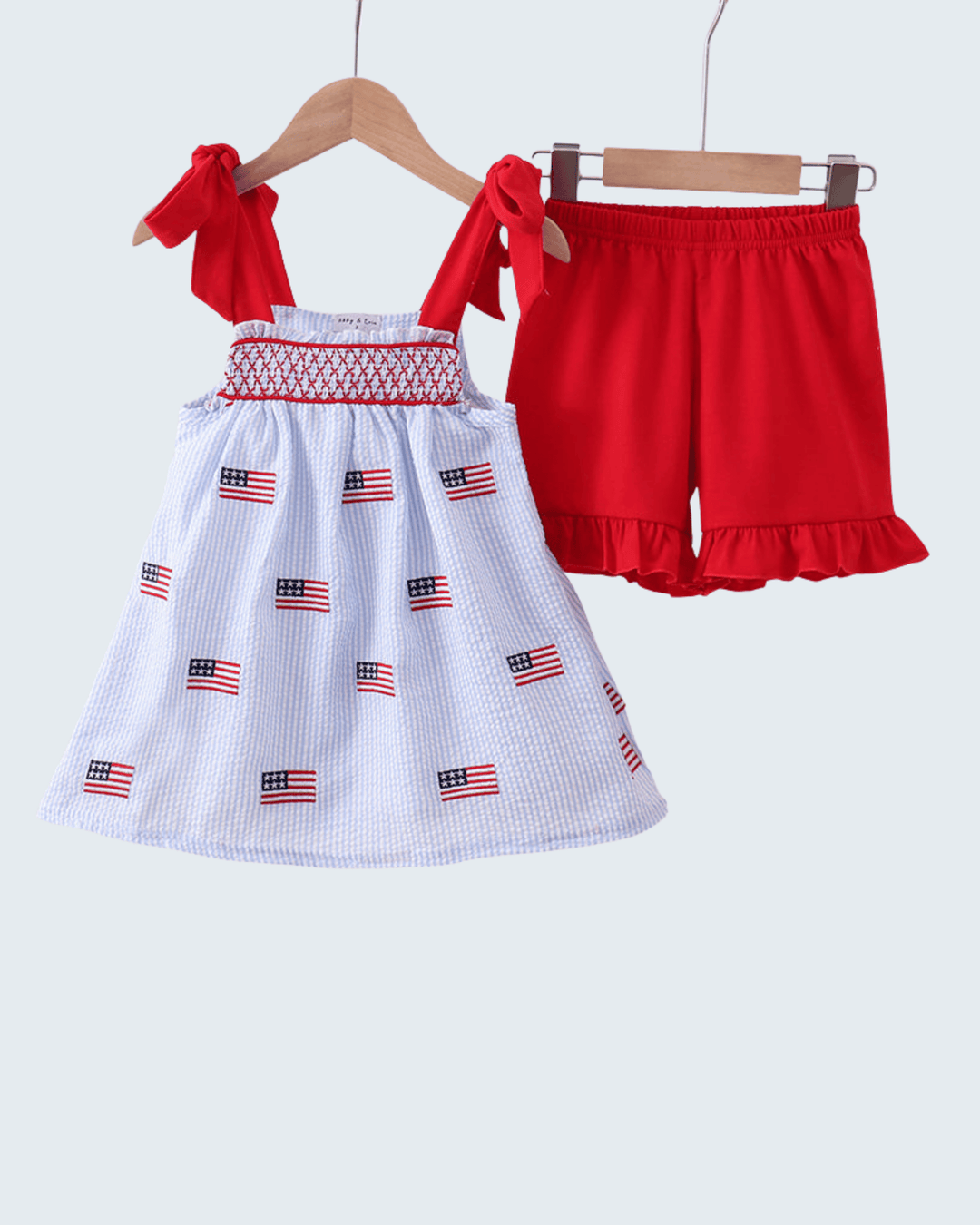 Children's outfit with red top and white skirt with American flag pattern on a white background