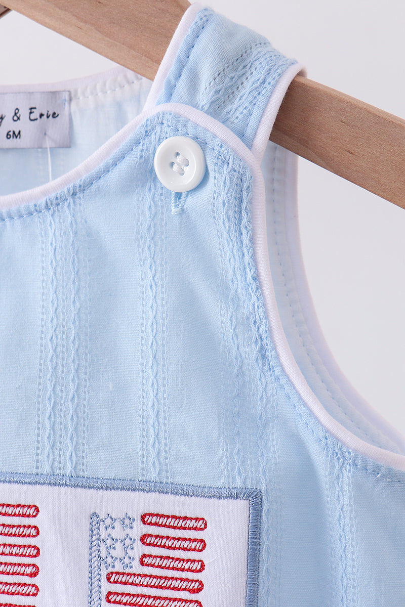Light blue baby romper with white buttons on a wooden hanger