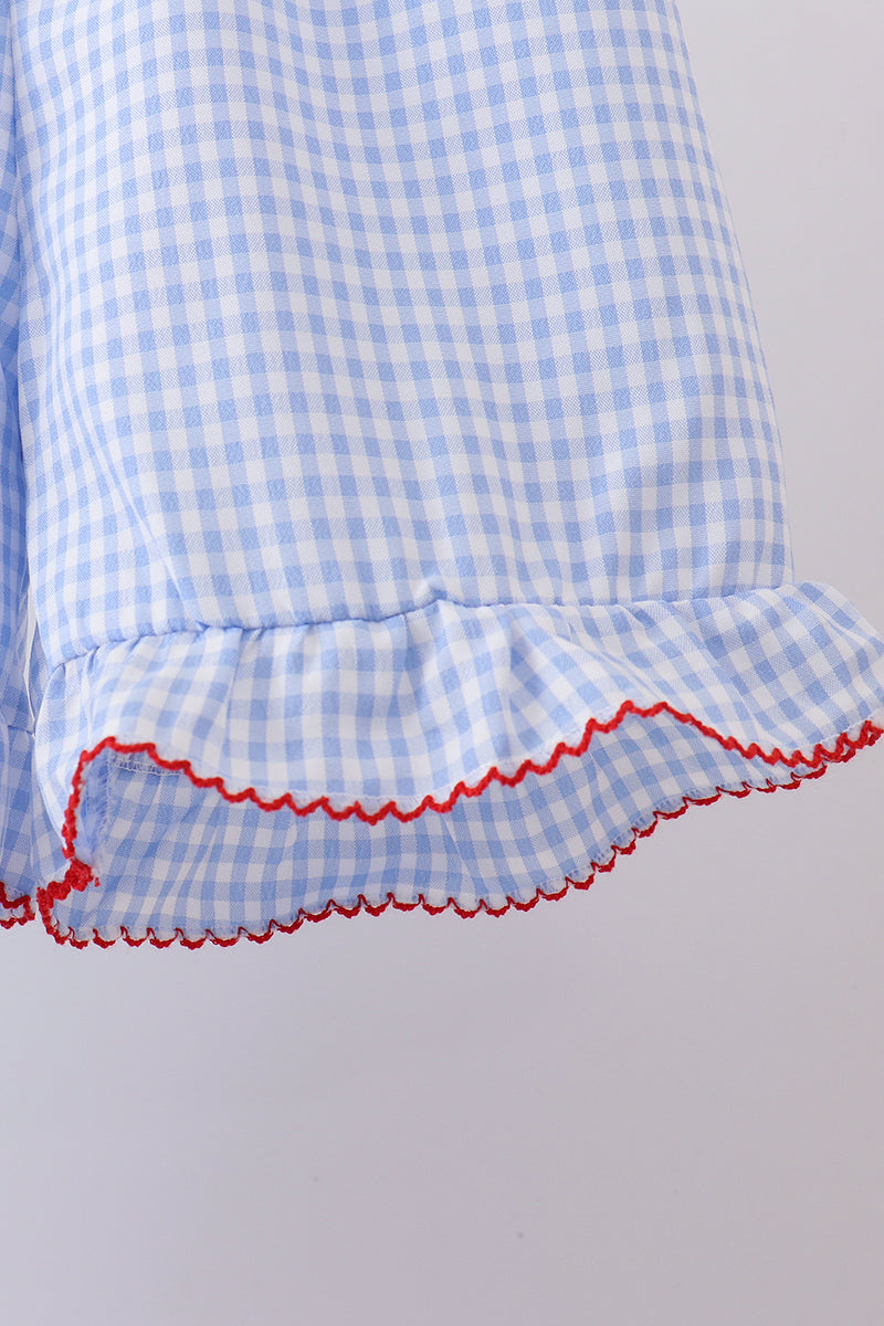 Close-up of a blue and white checkered dress with red trim on a light gray background