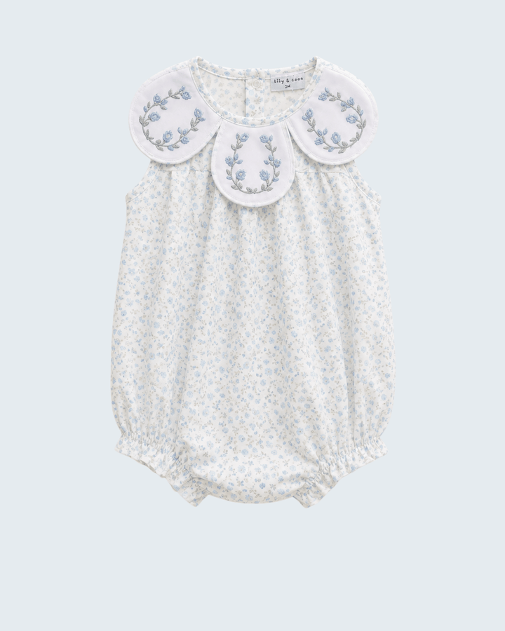 White baby romper with floral embroidery on a light gray background