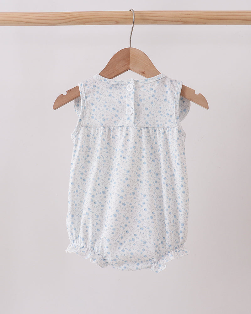 Baby romper with floral pattern on a wooden hanger against a light background