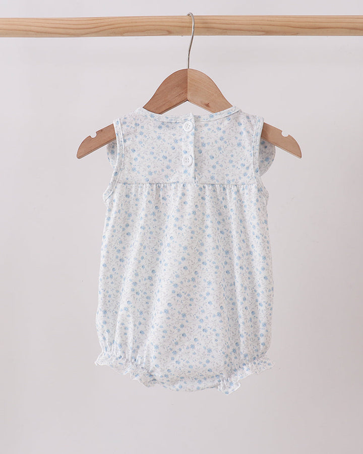 Baby romper with floral pattern on a wooden hanger against a light background