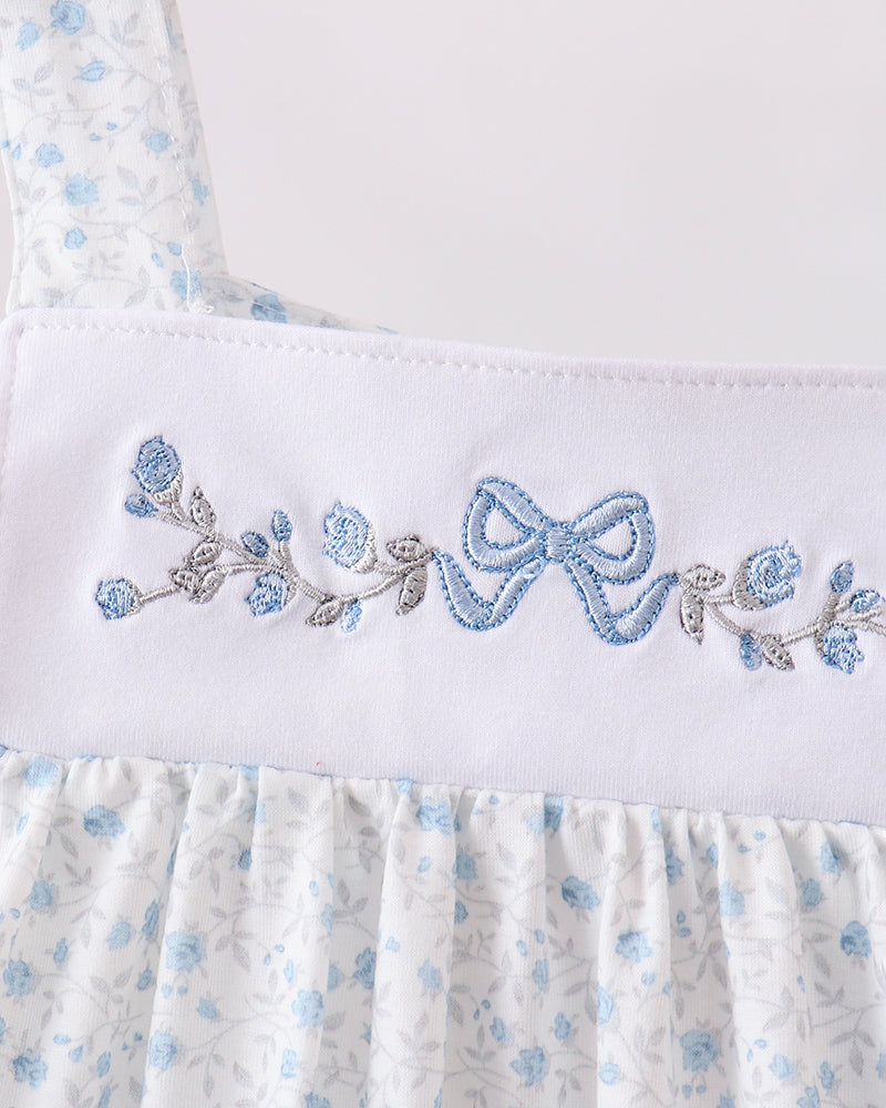 White dress with blue floral embroidery on a white background