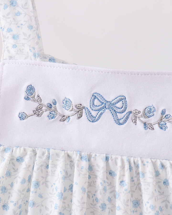 White dress with blue floral embroidery on a white background