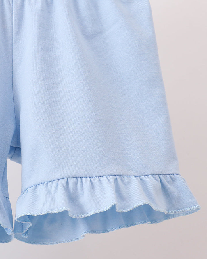 Light blue shorts with ruffled hem on a beige background