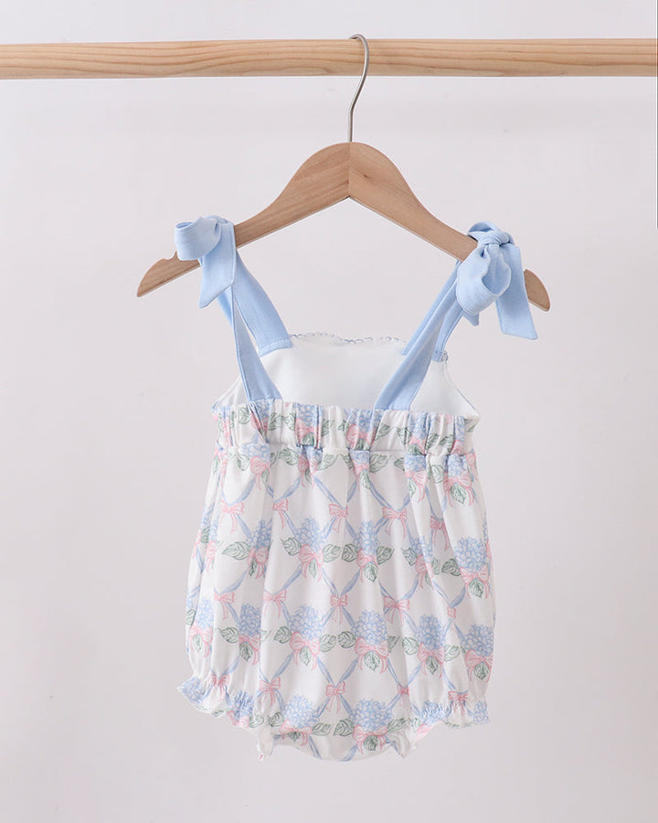 Baby romper with floral pattern and blue straps on a hanger against a white background