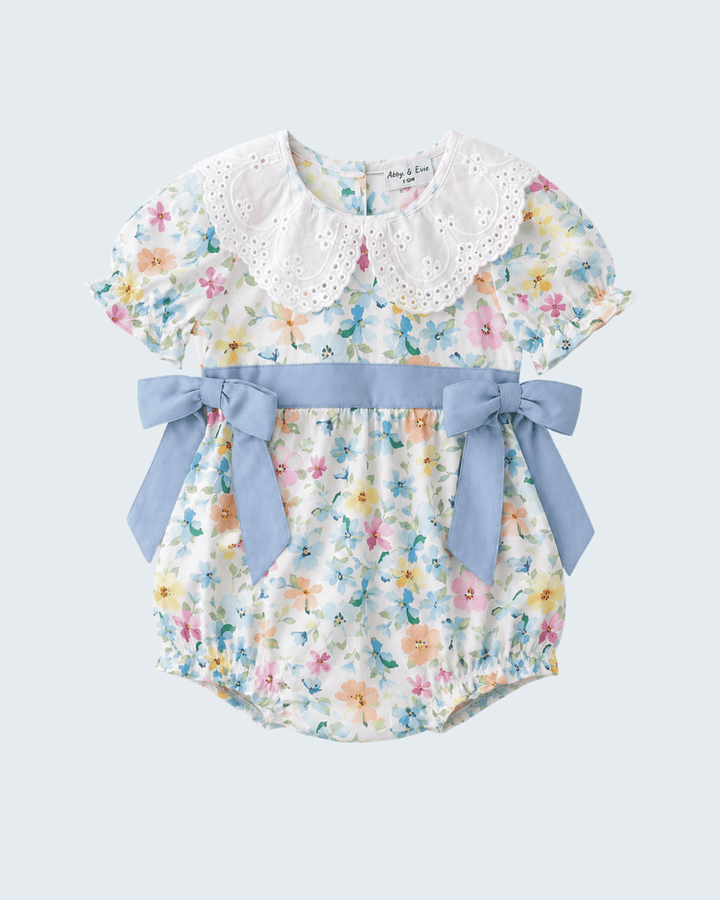 Floral baby romper with a blue bow on a light gray background