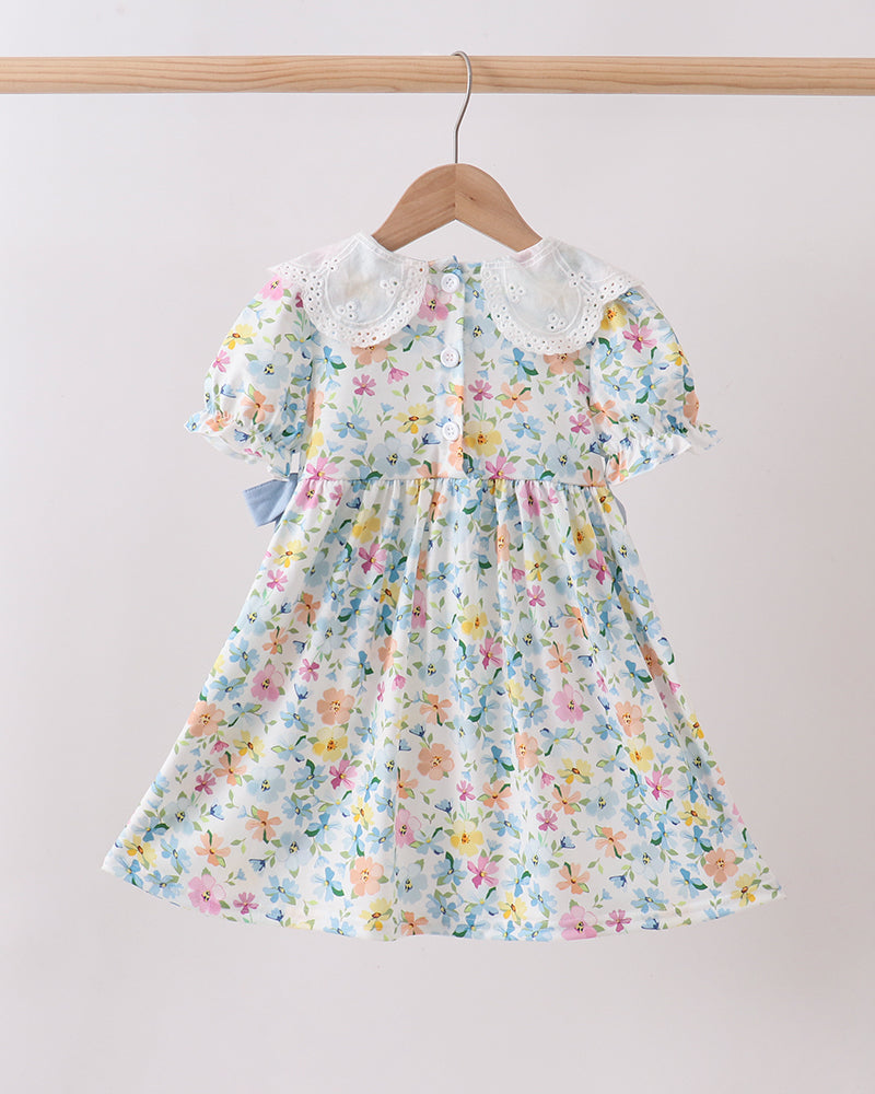 Floral dress hanging on a wooden hanger against a light background