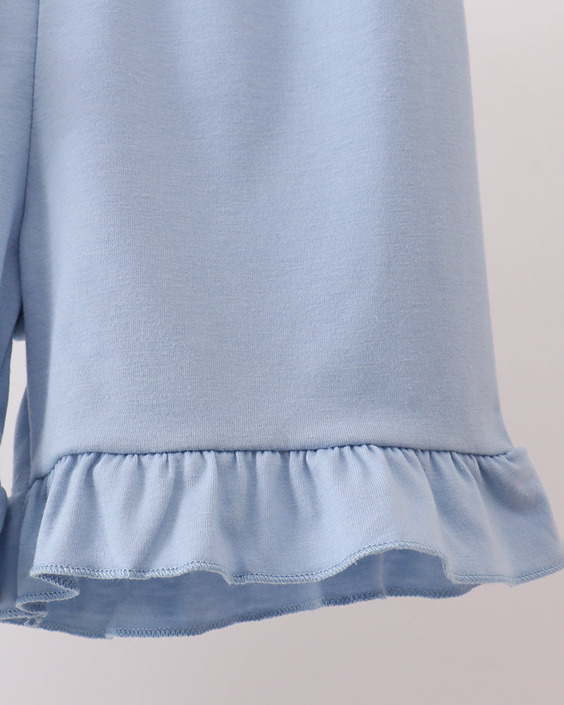 Light blue shorts with ruffled hem on a neutral background